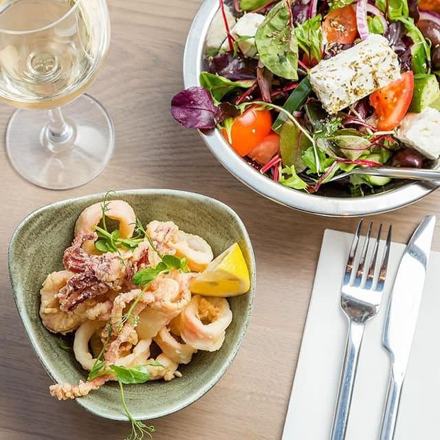 Fried kalamari and a Greek salad on the table at Ousia Charlotte Street